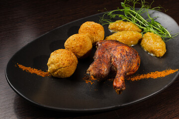 Very healthy roast duck thigh with potatoes and greens on a black plate on a wooden table serving in a restaurant. nice decoration of the dish. diet food in a restaurant. duck in the foreground