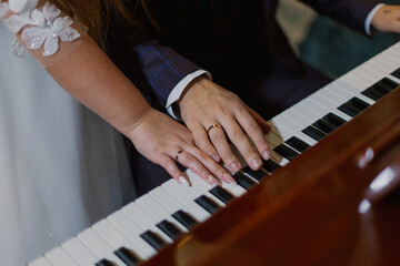 Fototapeta premium Beautiful hands with newlyweds rings on piano keys