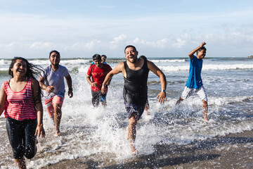 Happy latin friends jumping and running at beach at pacific ocean in Acapulco Mexico Latin America,...