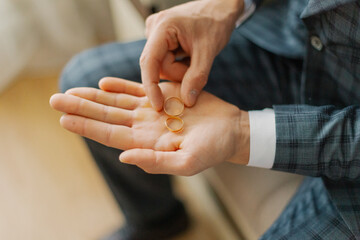 A young groom on his wedding day holds wedding gold rings in his hands, he is very happy. rings on the boat