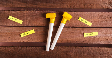 Happy April Fools Day, whistles and funny notes on wooden background top view web banner