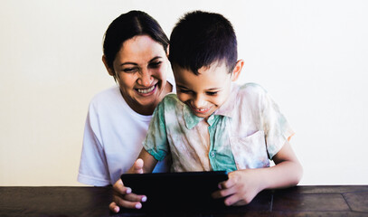 Family, Latin mother and son having fun playing with tablet computer at home, Mom and boy enjoy technology together