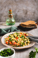 Tabbouleh salad with bulgur, tomato and parsley on a plate on the table vertical view