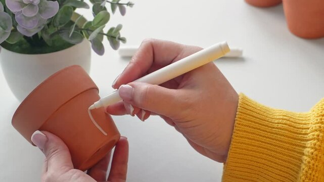 Creative hand painting on clay pots with delicate floral designs in natural setting