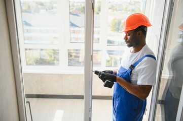 Worker installing plastic window indoors
