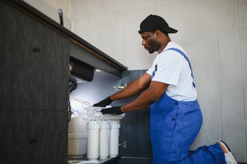Technician installing reverse osmosis equipment under the sink