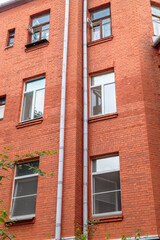 Obraz premium The facade of the old red brick building that was built 100 years ago against the backdrop of the White Sky. Ancient decoration of the building. Restoration of buildings. Old details. Distribution