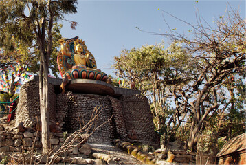 A large colourful statue of a diety seated on an ornate pedestal