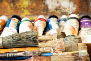 Artist paint brushes and tubes of paint in an old wooden paint splattered box