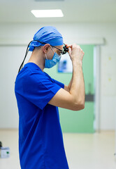 Surgeon ready for surgery. A medical professional in scrubs adjusts surgical equipment while...