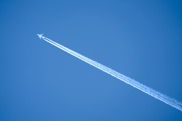 a twin engined jet liner aircraft in deep blue sky, contrails vapour trails
