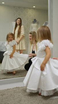 Little girl trying on a white dress. Concept of trying on clothes.