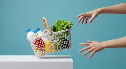A conceptual and minimalist stock image depicting a modern shopping basket suspended above a pair of outstretched hands, symbolizing online shopping, grocery delivery