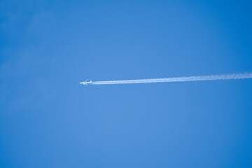a twin engined jet liner aircraft in deep blue sky, contrails vapour trails