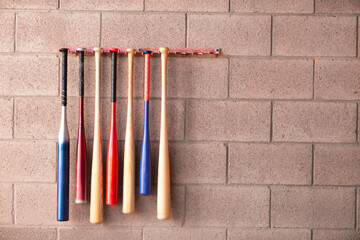 Wooden wood and aluminum little league baseball bats hanging on wall in dugout