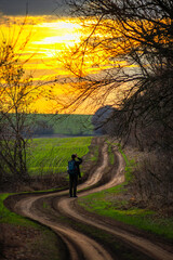 Photographer on the field , man with a camera , landscape photography in the forest , sunset and forest , green field with man , cameramen in nature 