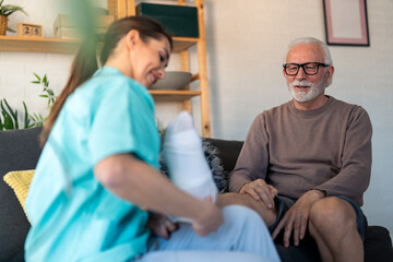 Professional Home Care Nurse Assisting Elderly Man With Medical Compression Stockings During Healthcare Visit