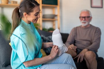 Compassionate Female Nurse Assists Elderly Male Patient in Wearing Anti-Thrombosis Stockings at Home