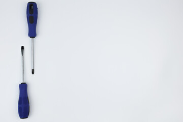 Two screwdrivers with blue handles lie opposite each other on a white background on the side with...