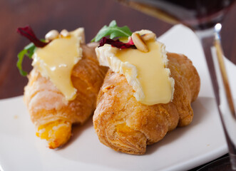 Dessert of french cuisine, mini croissant with camembert cheese at plate in cafe