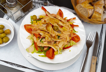 Ensalada de pollo, chicken salad with lettuce, tomato and olives on a plate