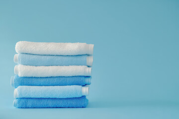 Neatly folded blue and white towels on pastel blue background
