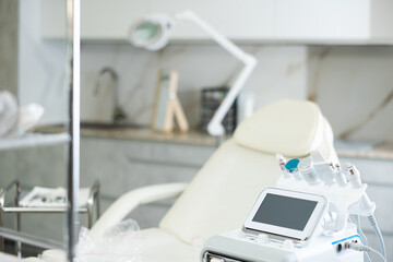 Professional office of aesthetic medicine clinic with treatment chair for patients and modern hydrogen oxygen beauty machine with different attachments to provide specialized skincare procedures