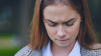 Lonely young student sitting on park bench, shoulders slumped, experiencing emotional distress with...