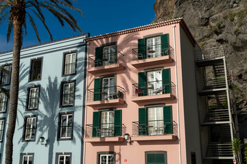 Naklejka premium Colorful Houses with Palm Trees by a Rocky Cliff in a Coastal Town