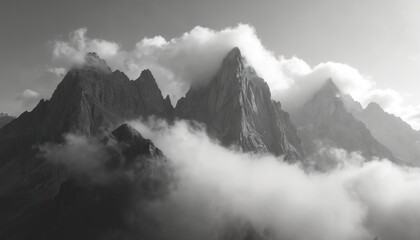Black white photo of misty mountain peaks shrouded in fog. Dramatic scenic nature landscape with clouds covering summits. Wilderness, outdoors, adventure, travel, exploration concept.