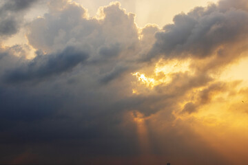 Dramatic sunset sky over Caribbean Sea with dark storm clouds and golden sun rays breaking through. Mexico.