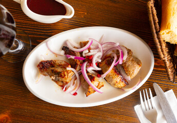 Traditional oriental grilled pork meat shashlik served with marinated onion