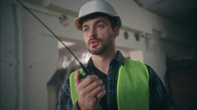 Serious Caucasian man worker executive guy builder mechanic talking walkie talkie architect male ordering architectural project in factory controller speak construction engineer control manufacturing
