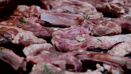 Sizzling lamb ribs coated in garlic and rosemary, grilling over hot coals, releasing savory aromas and promising delectable outdoor dining experience