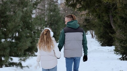 Snowy forest path with father and daughter walking hand in hand, sharing tender moment amid snow...
