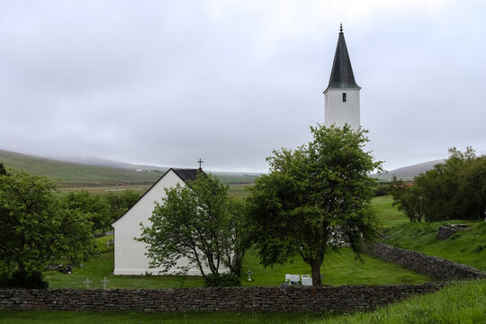Holar Church rising over the Icelandic landscape in a cloudy day