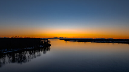 Delta BC Canada - February 11th 2025: Sunset at Deas Island Regional Park waterfront with moonrise over mountain