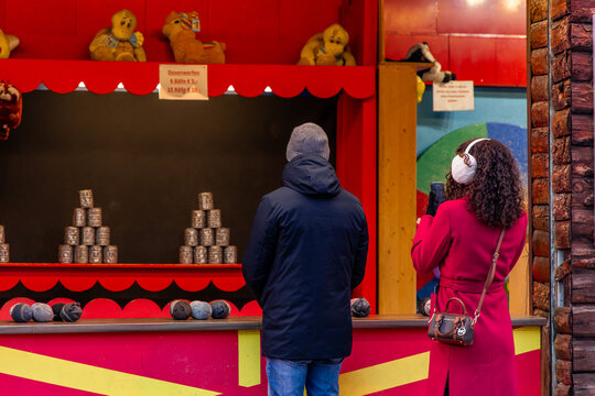 Tourists playing and taking pictures at a can knockdown game in Vienna Christmas Market