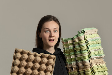 A woman passionately sorts recyclables at a recycling center, showcasing her dedication to environmental conservation while holding stacks of cardboard egg cartons