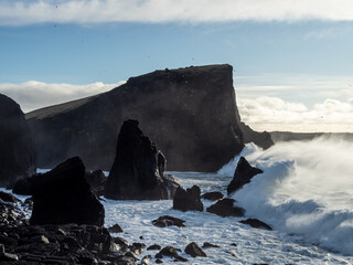 Valahnúkamöl’s rugged coastline showcases towering basalt sea stacks and sheer cliffs as powerful Atlantic waves crash against the volcanic shore, creating a breathtaking, dramatic landscape