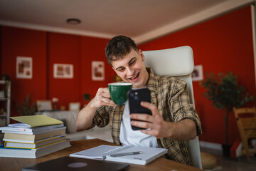 young man student drink coffee and have video call on mobile phone