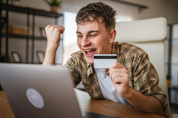 young man enjoy at online shopping use credit card and laptop at home
