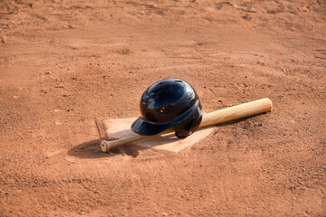 Little league wood baseball bat and batting helmet on homeplate