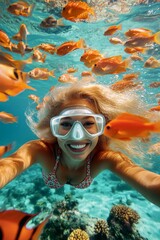 Fototapeta premium Many tropical fish swim next to her. A stunning and sexy happy black young woman with blond hair in a swimming mask and fins snorkeling among the corals. Bright commercial style image.