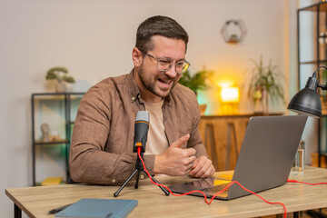 Happy excited blogger man recording podcast at desk, giving workshop, webinar. Young Caucasian guy...