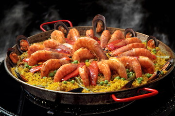 Shrimp Paella Valenciana being prepared in the paellera on a black background