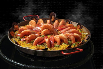 Shrimp Paella Valenciana being prepared in the paellera on a black background
