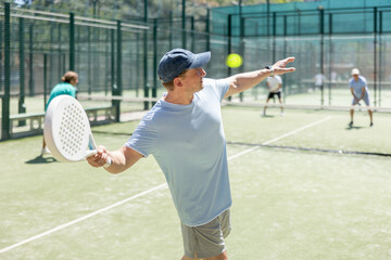 Four men practice playing padel on an outdoor tennis court