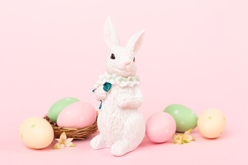 Easter bunny with painted eggs on color background