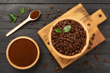 Roasted coffee beans with leaves on wooden background,top view